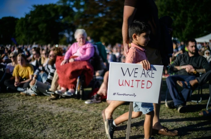 Un petit garçon tient une pancarte "nous sommes unis" lors d'un rassemblement en mémoire des victimes des attaques contre les mosquées de Christchurch, le 24 mars 2019 dans cette ville néo-zélandaise