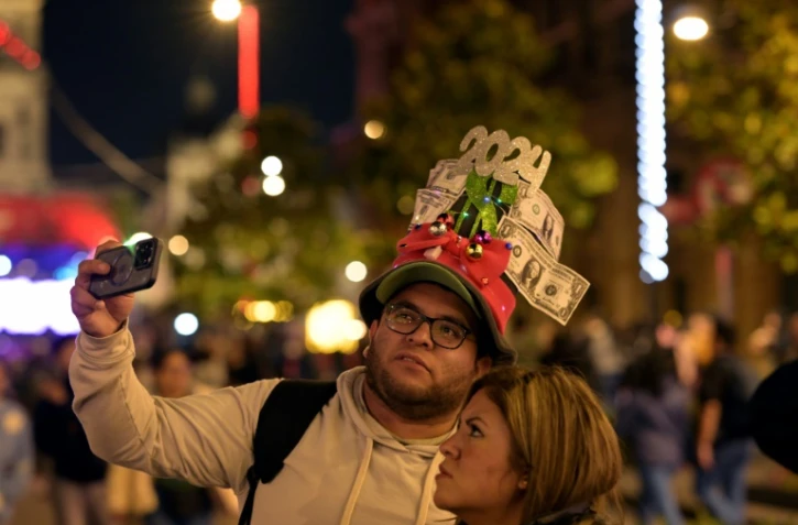 Un couple prend un selfie sur le Zocalo à Mexico, le 30 décembre 2023