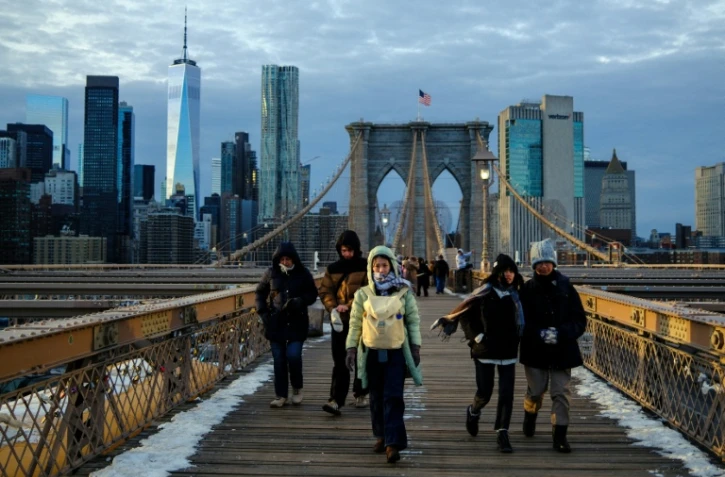 Des passants bravent le froid en traversant le pont de Brooklyn, dans le quartier de Manhattan à New York, le 21 janvier 2026