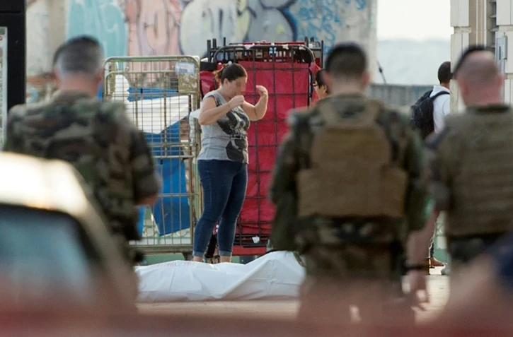Une femme réagit devant le corps de l'homme suspecté d'avoir tué deux jeunes femmes à l'arme blanche avant d'être abattu par des militaires à la gare Saint-Charles de Marseille, le 1er octobre 2017