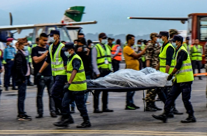 Des secouristes portent le corps d'une victime du crash d'un avion dans l'Himalaya, transporté par hélicoptère à Katmandou, le 30 mai 2022 au Népal