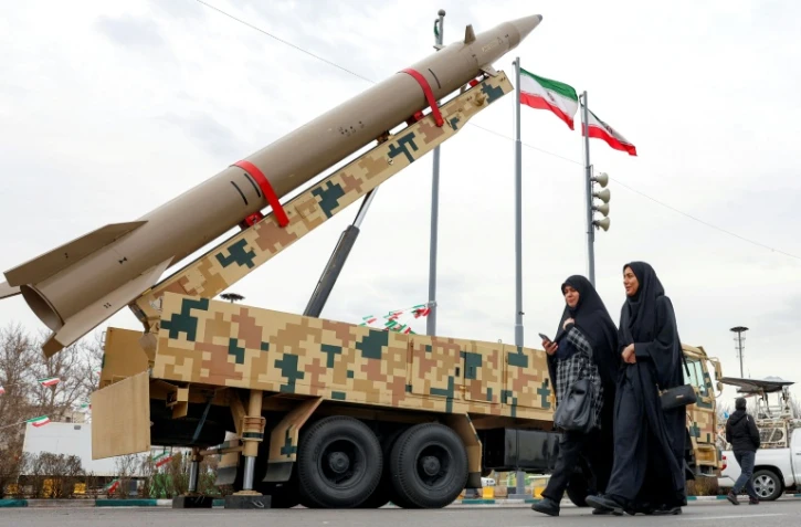 Des femmes passent devant un lanceur de missile balistique à Téhéran, le 11 février 2026, lors d'un rassemblement marquant le 47e anniversaire de la révolution islamique de 1979 en Iran
