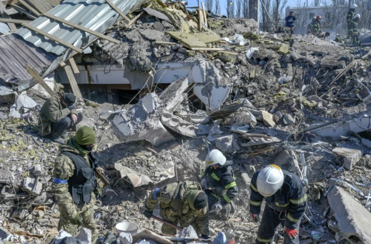 Des soldats ukrainiens et des secouristes recherchent des victimes dans les ruines d'une caserne militaire bombardée à Mykolaïv, en Ukraine, le 19 mars 2022
