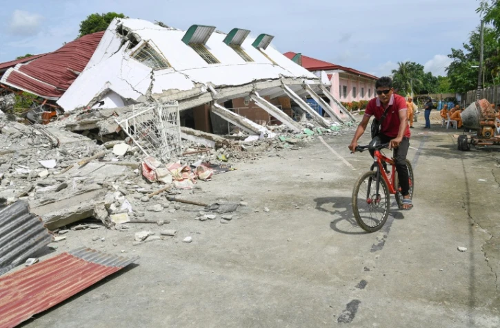 Un homme passe à vélo devant un bâtiment effondré où trois personnes ont été retrouvées mortes après un séisme à Bogo, dans la province de Cebu aux Philippines, le 2 octobre 2025