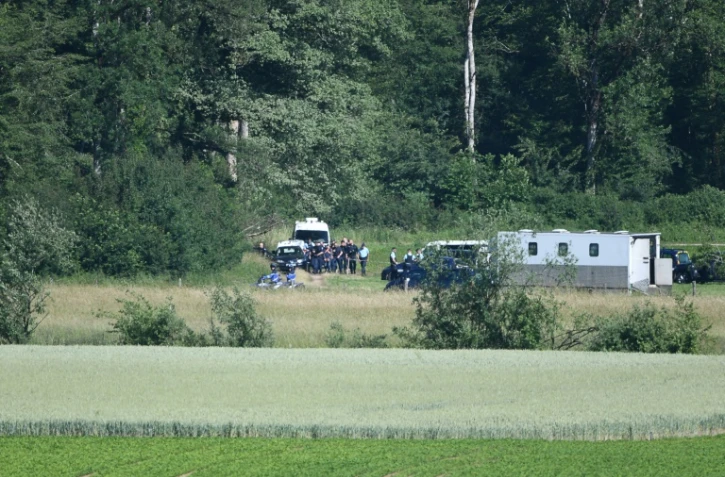 Jonathann Daval (C), entouré de gendarmes, le 17 juin 2019, lors de la reconstitution du meutre d'Alexia Daval, aux abords du bois d'Esmoulins où son corps avait été retrouvé.