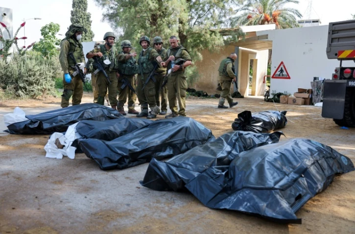 Des soldats israéliens se préparent à retirer les corps des habitants de Kfar Aza, tués lors d'une attaque menée par le Hamas le 7 octobre, à la frontière de la bande de Gaza, le 10 octobre 2023
