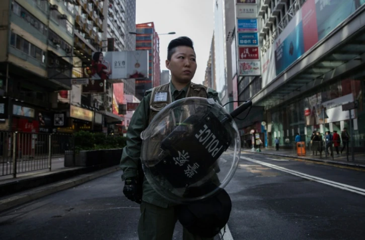 Une femme de la police anti-émeutes de Hong Kong le 9 février 2016 devant une rue interdite d'accès après les heurts de la nuit entre la police et des protestataires dans le quartier de Mongkok à Hong Kong le 9 février 2016 