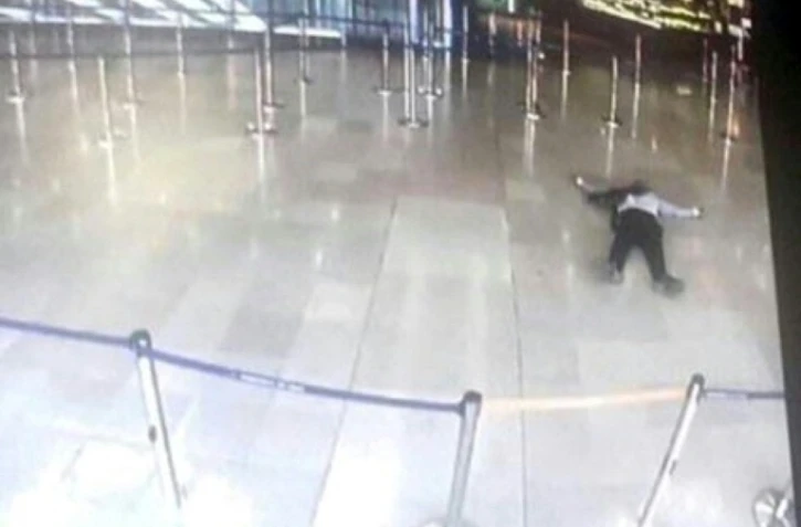 Photo prise sur un écran de télévision le 18 mars 2017 montrant un homme gisant sur le sol à l'aéroport d'Orly après avoir pris une arme à un militaire