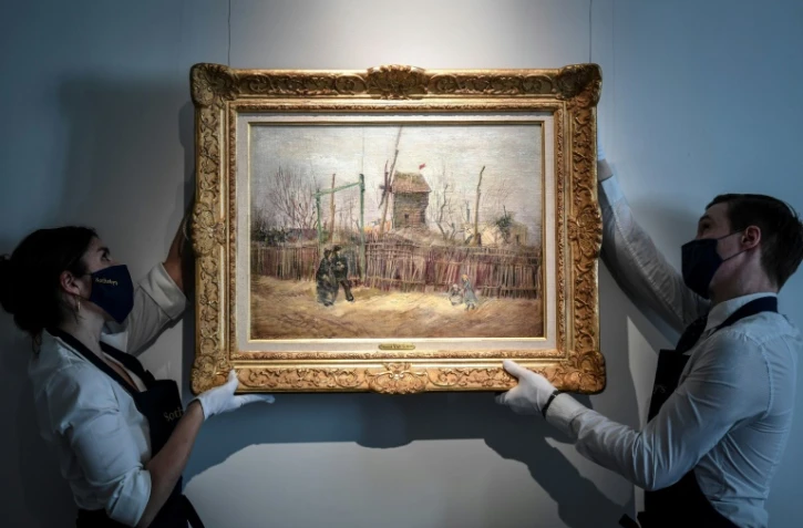 Des employés mettent en place l'oeuvre du peintre néerlandais Vincent Van Gogh "Scène de rue à Montmartre" (1887) au sein de la maison d'enchères Sotheby's à Paris le 24 février 2021