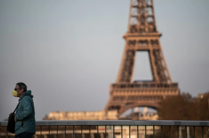 Un homme portant un masque de protection traverse le pont de Grenelle, le 18 mars 2020 à Paris, au lendemain du confinenemnt instauré en France pour lutter contre le coronavirus