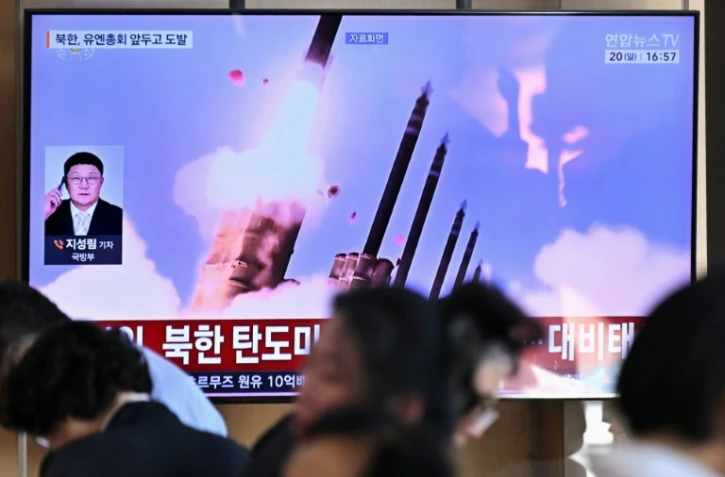 Des personnes sont assises près d'un écran TV diffusant un bulletin d'information avec des images d'archives d'un essai de missile nord-coréen, le 20 septembre 2026 dans une gare de Séoul