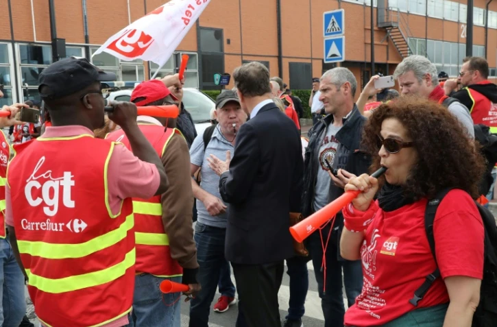 Un actionnaire quittant l'assemblée générale de Carrefour le 15 juin 2018 à Aubervilliers (Seine-Saint-Denis) parle avec des syndicalistes CGT