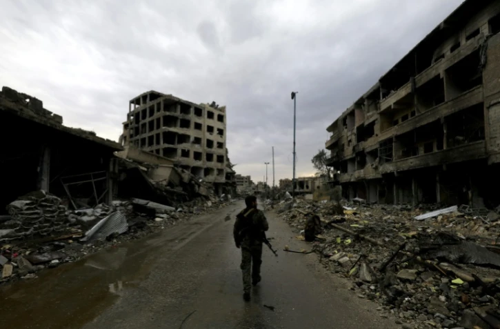 Un membre des "Forces démocratiques syriennes" marche au milieu des décombres dans une rue de Raqa, en Syrie, le 28 octobre 2017