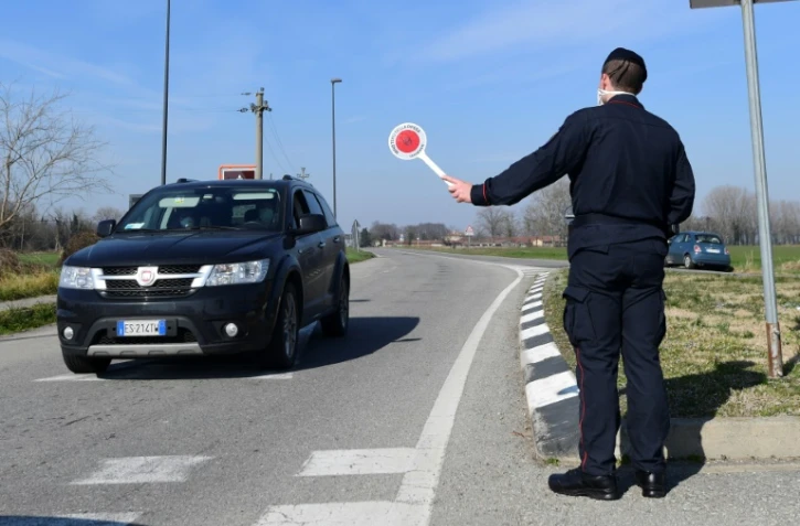 Un policier italien stoppe une voiture à un point de contrôle près de la petite ville de Castiglione d'Adda, au sud-est de Milan, le 24 février 2020.  