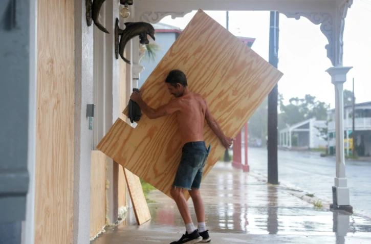 Un homme barricade un bâtiment avant l'arrivée de la tempête Debby, à Cedar Key en Floride le 4 août 2024