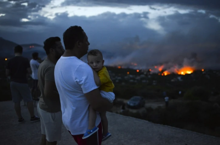 Des Grecs observent un feu de forêt à Rafina dans la banlieue d'Athènes, en Grèce