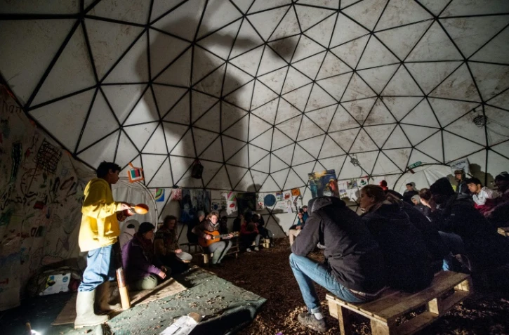 Des migrants assistent à un concert dans un théâtre de fortune de la "Jungle" de Calais, dans le Pas-de-Calais, le 25 novembre 2015