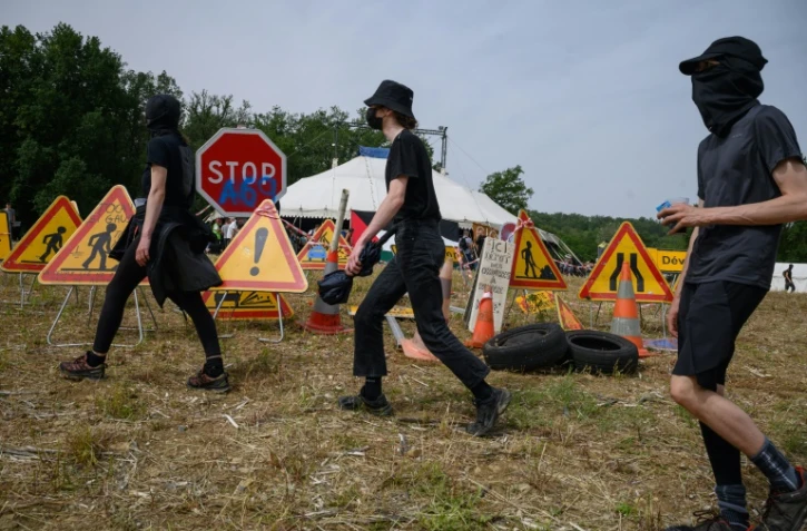 Manifestants devant plusieurs panneaux routiers de travaux, lors de la mobilisation contre l'autoroute A69, près de Puylaurens (Tarn), le 8 juin 2024