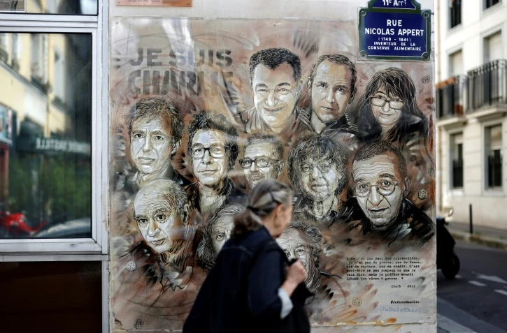 Une femme passe devant l'oeuvre de l'artiste de rue et peintre Christian Guemy, connu sous le nom de C215, en hommage aux membres de l'équipe de Charlie Hebdo assassinés en janvier 2015 par des jihadistes à Paris, le 31 août 2020