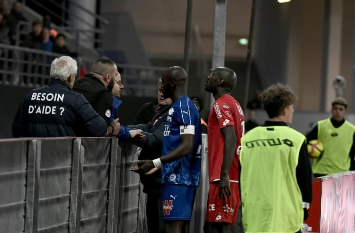 Le capitaine amiénois Prince Désir Gouano (g) se rapproche des supporters après des cris racistes à son égard et l'interruption pendant quelques minutes du match face à Dijon le 12 avril 2019