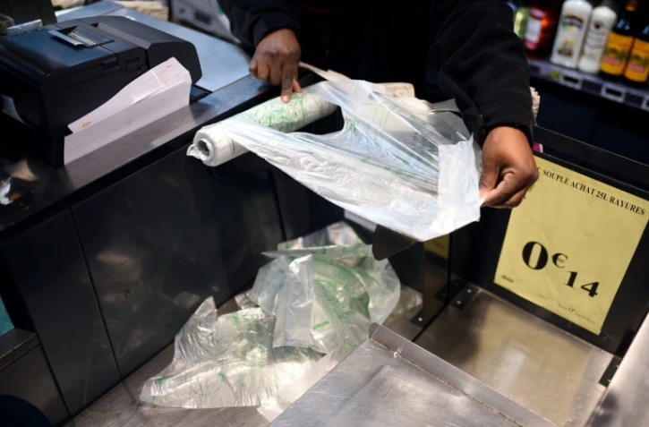 Un employé de supermarché prend un sac plastique à usage unique à Paris, le 28 décembre 2015