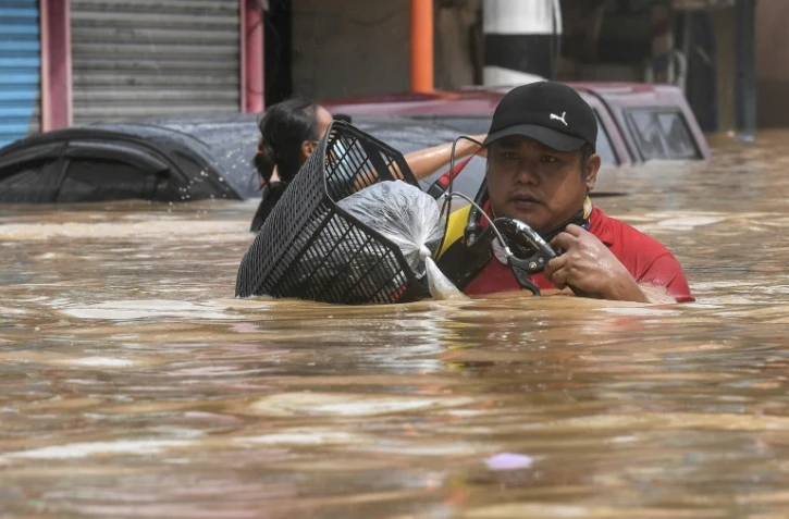 Un habitant porte son vélo en avançant dans une rue inondée après le passage du typhon Vamco, à Marikina City, quartier de Manille, le 12 novembre 2020