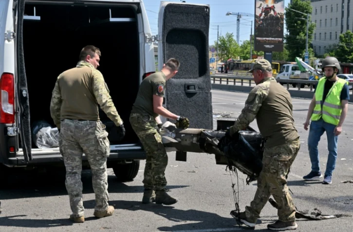 Des policiers spécialisés ukrainiens chargent des débris de missiles russes dans une voiture  le 29 mais 2023 à Kiev