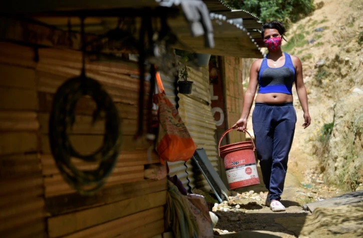 Yeimy Martinez porte un seau d'eau pour cuisiner, le 26 mai 2020 à Bogota, en Colombie