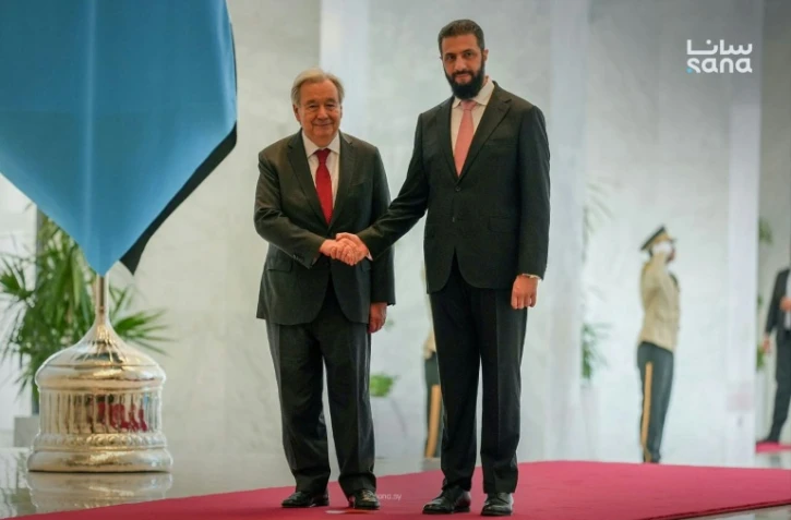 Photo fournie par l'agence de presse syrienne Sana le 25 juillet 2026 montrant le secrétaire général de l'ONU, Antonio Guterres (G) serrant la main du président syrien Ahmad al-Chareh (D) au palais présidentiel à Damas