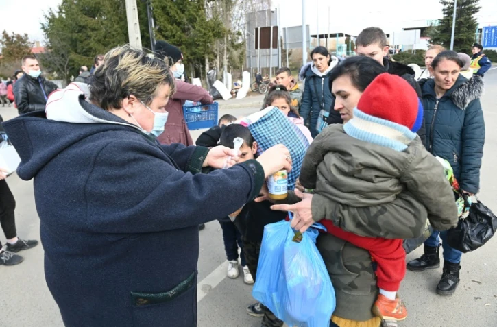 Une femme donne de la nourriture à une réfugiée ukrainienne et son enfant, à Tiszabecs (Hongrie), le 27 février 2022