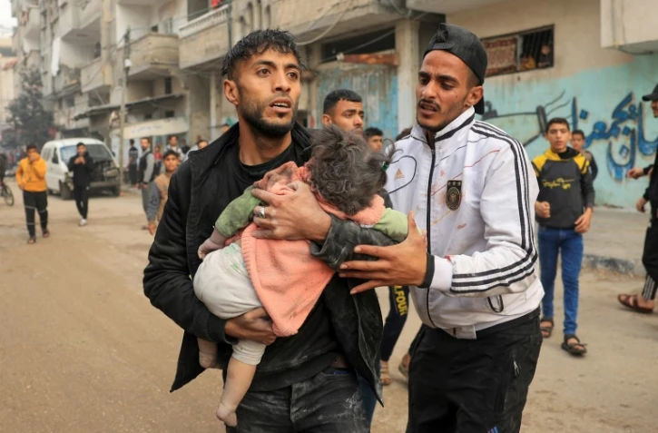 Un homme porte un enfant blessé lors d'un bombardement israélien, le 14 décembre 2023 à Rafah dans la bande de Gaza