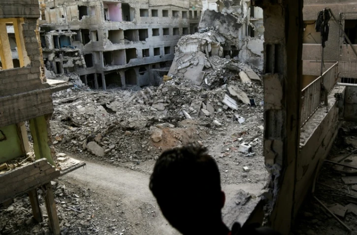 Un jeune Syrien regarde du balcon d'um immeuble endommagé les destructions dans la localité d'Aïn Tarma dans l'enclave rebelle dans la Ghouta orientale, bombardée par le régime, le 2 mars 2018 