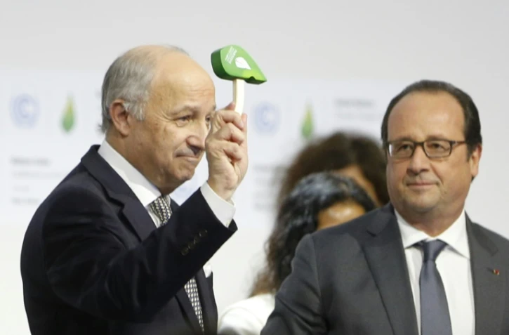Le président de la COP21 Laurent Fabius donne un coup de marteau symbolique pour marquer l'officialisation de l'accord sur le climat, au côté du président français François Hollande, le 12 décembre 2015 au Bourget