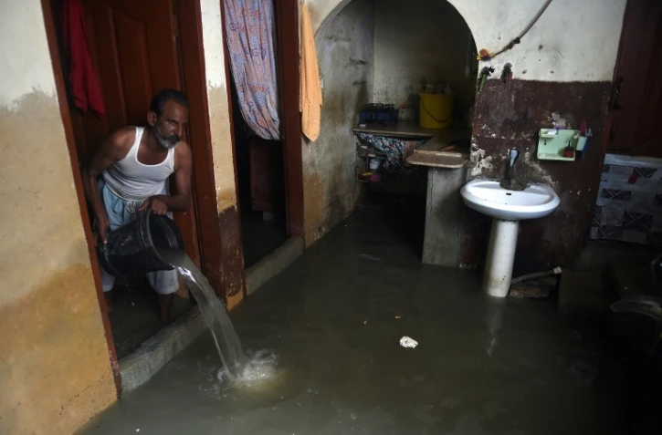Un habitant de Karachi, dans le sud du Pakistan, écope avec un seau l'eau de son logement inondé par les pluies de mousson, le 26 juillet 2022