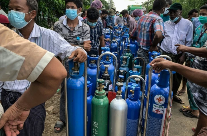 Des gens attendent pour remplir des bouteilles d'oxygène pour leurs proches atteints de Covid-19, à Rangoun le 14 juillet 2021