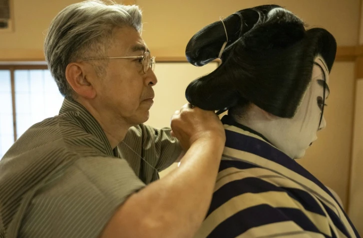Le maître perruquier Tadashi Kamoji (g) aide l'acteur Tanenosuke Nakamura à mettre sa perruque avant une représentation au théâtre Kabuki-za à Tokyo, le 13 avril 2026