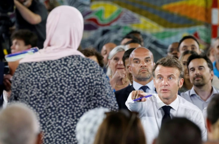 Le président français Emmanuel Macron (d) parle à une mère dans le public présent dans un gymnase du quartier marseillais de La Busserine, le 26 juin 2023