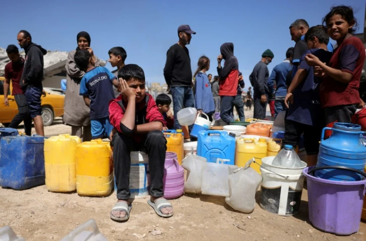 Des Palestiniens attendent de pouvoir obtenir de l’eau dans un camp de personnes déplacées à Gaza-Ville, le 20 mai 2025, sur fond de guerre entre Israël et le mouvement palestinien Hamas