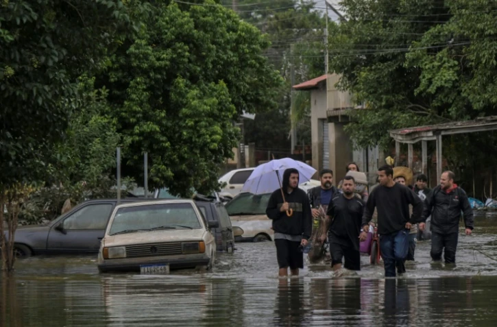 Des habitants se déplacent dans une rue inondée de la ville de Canoas, dans le sud du Brésil, le 13 mai 2024