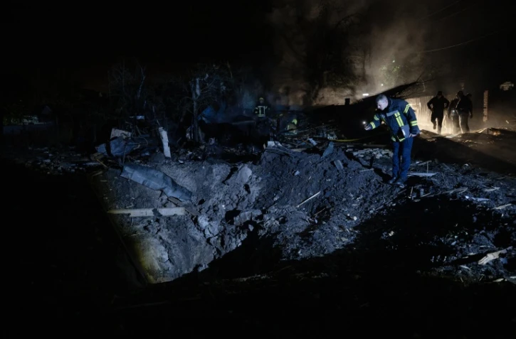 Un pompier ukrainien examine un cratère après une frappe de missile russe qui a touché des habitations à Kiev dans la soirée du 21 octobre 2026