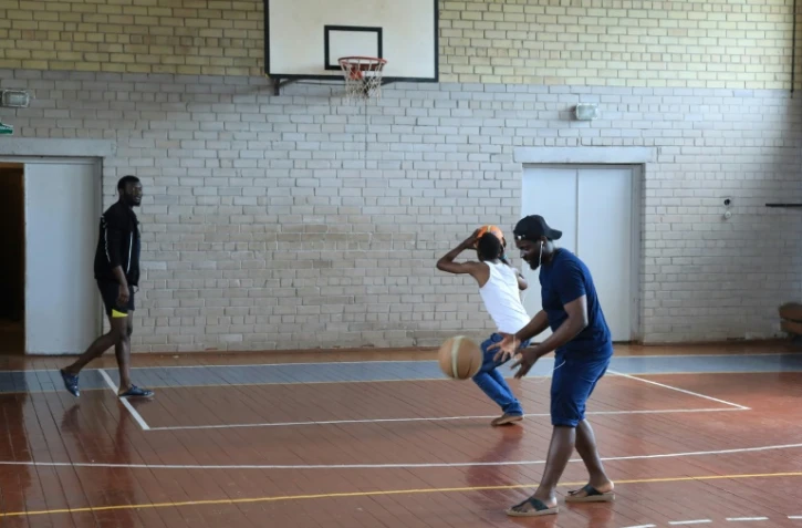 De jeunes migrants jouent au basket dans le gymnase d'une ancienne école transformée en hébergement, à Vydeniai, en Lituanie, le 29 juillet 2021