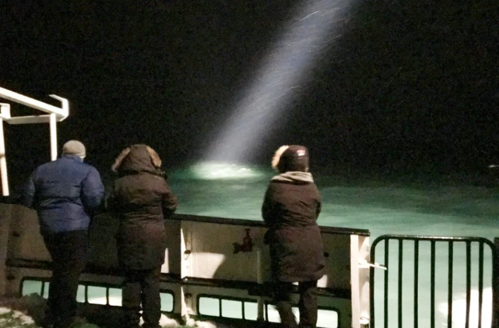 Des personnes à bord d'un bateau qui participaient aux recherches d'un hélicoptère disparu dans l'Arctique, le 26 octobre 2017 