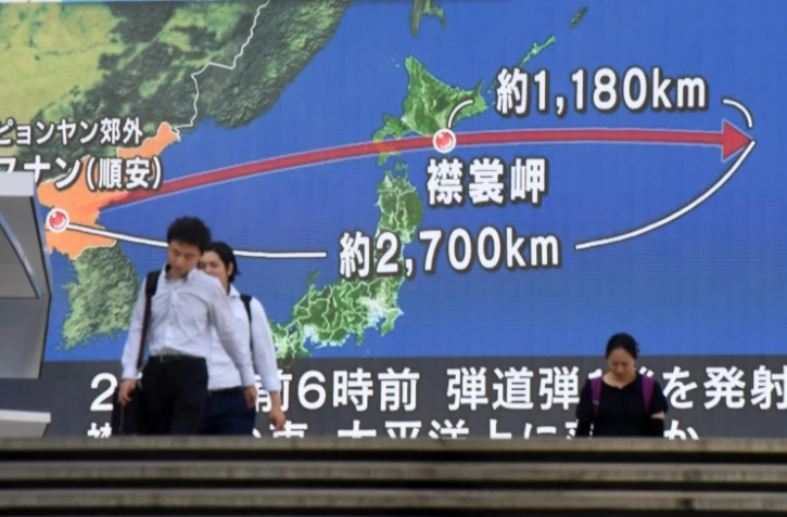 Des passants devant un écran géant à Tokyo montrant le trajectoire du missile nord-coréen, le 29 août 2017