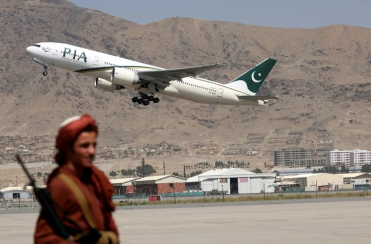 Un combattant taliban monte la garde alors qu'un avion de la compagnie Pakistan International Airlines, premier vol commercial depuis le retour au pouvoir des islamistes le mois dernier, décolle de l'aéroport de Kaboul, le 13 septembre 2021