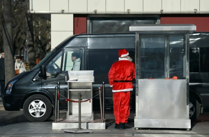 Un agent de sécurité en costume de père Noël à l'entrée d'un parking le 24 décembre 2014 à Pékin 