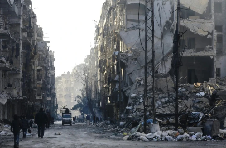 Des habitants des ex-quartiers rebelles d'Alep passent devant des immeubles détruits, le 21 janvier 2017 en Syrie