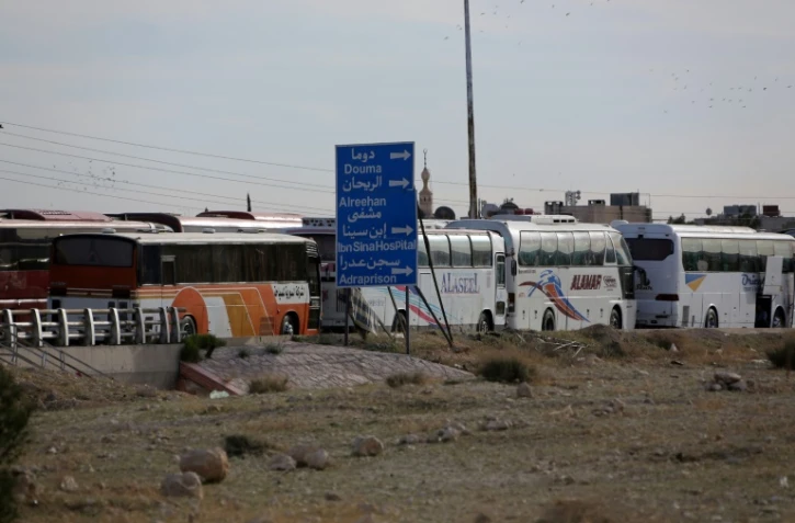 Les bus devant évacuer les rebelles et les civils de la ville rebelle de Douma, dans la Ghouta orientale, prÚs de Damas le 2 avril 2018