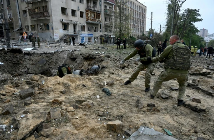 Des soldats retirent un fragment de missile dans un cratère après une frappe à Kharkiv, le 6 octobre 2023 dans l'est de l'Ukraine