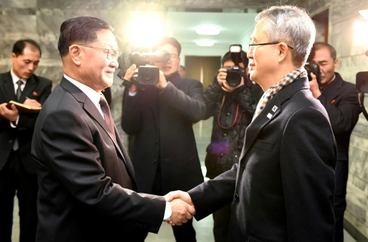 Photo fournie par le ministère de la réunification montrant Kwon Hyok-Bong (g), haut responsable du ministère nord-coréen de la culture, accueillant Lee Woo-Sung du ministère de la culture sud-coréenne, lors de leur rencontre au village frontalier de Panmunjom, dans la zone démilitarisée, le 15 janvier 2018