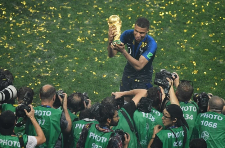 Kylian Mbappé brandit fièrement le trophée de la Coupe du monde, devant une meute de photographes, le 15 juillet 2018 à Moscou 
